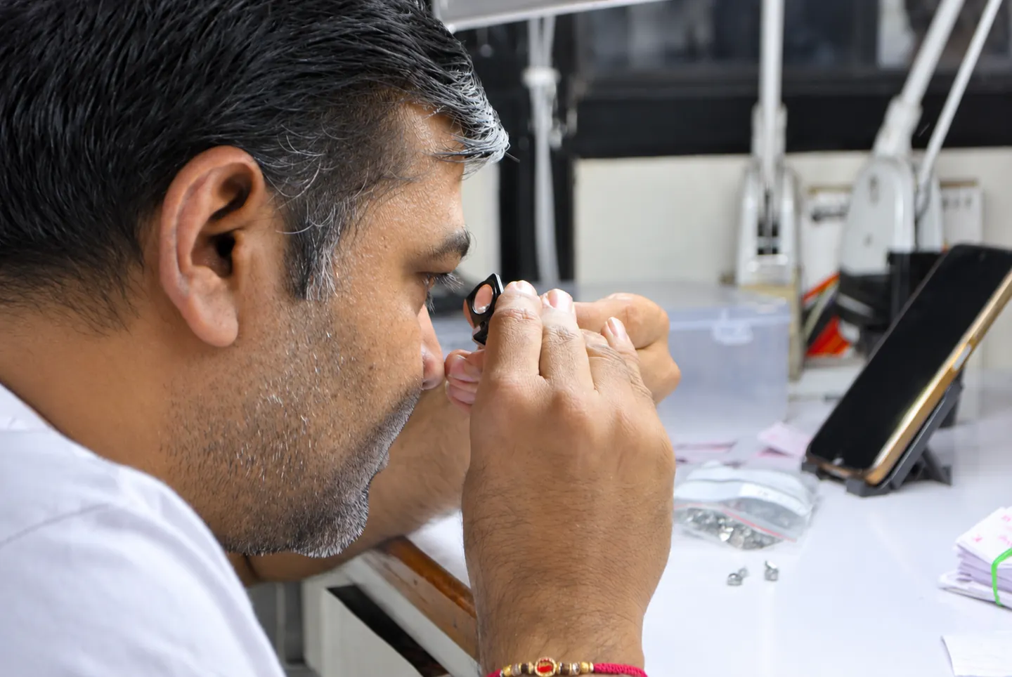 Sitaram craftsperson inspecting a stone through a loupe; exposure-adjusted photograph