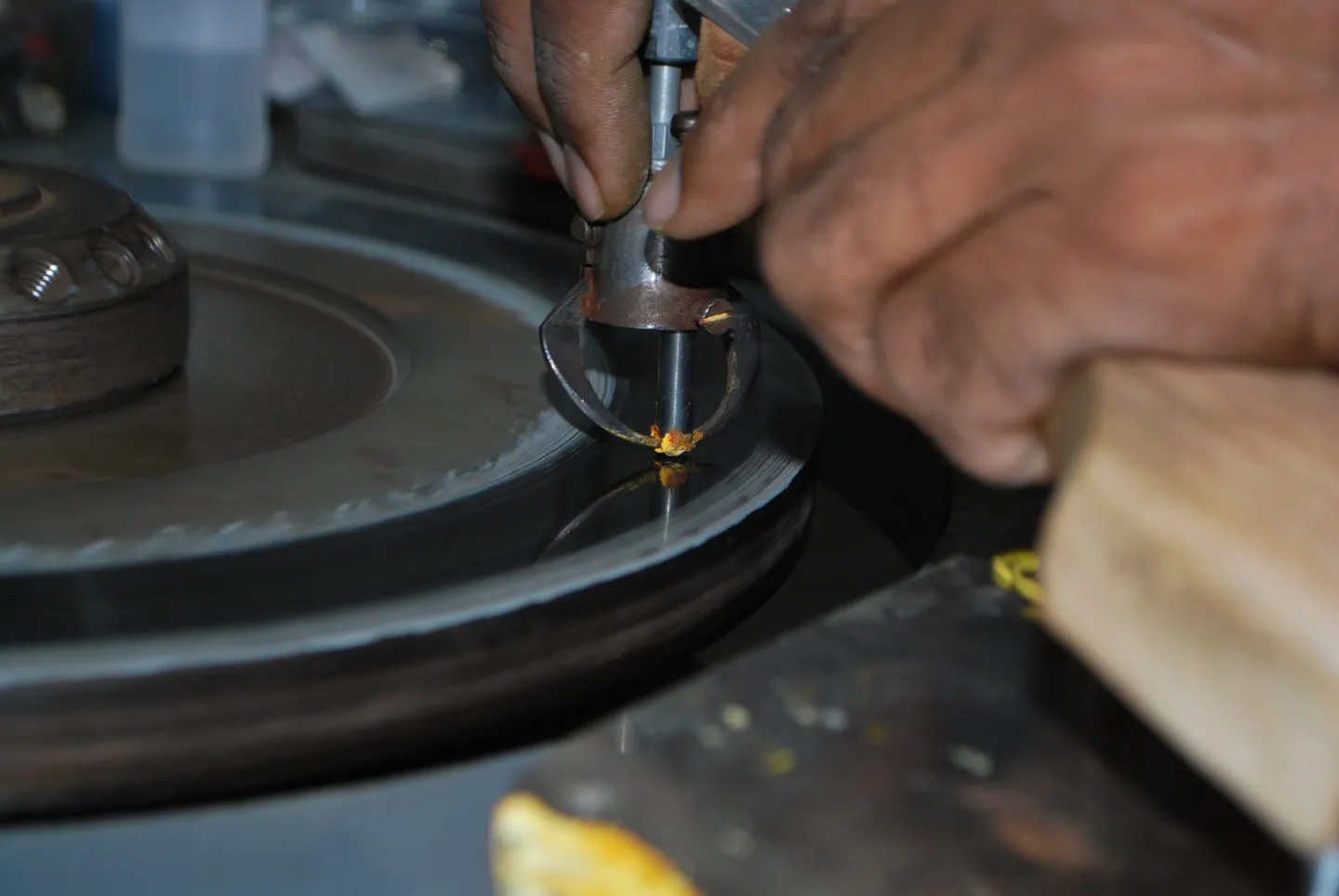 A craftsperson's hands at a polishing wheel