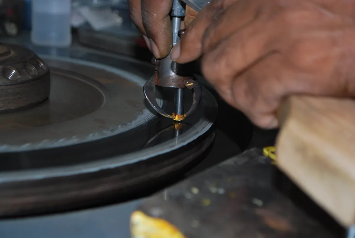 Hands holding a diamond against a polishing scaife